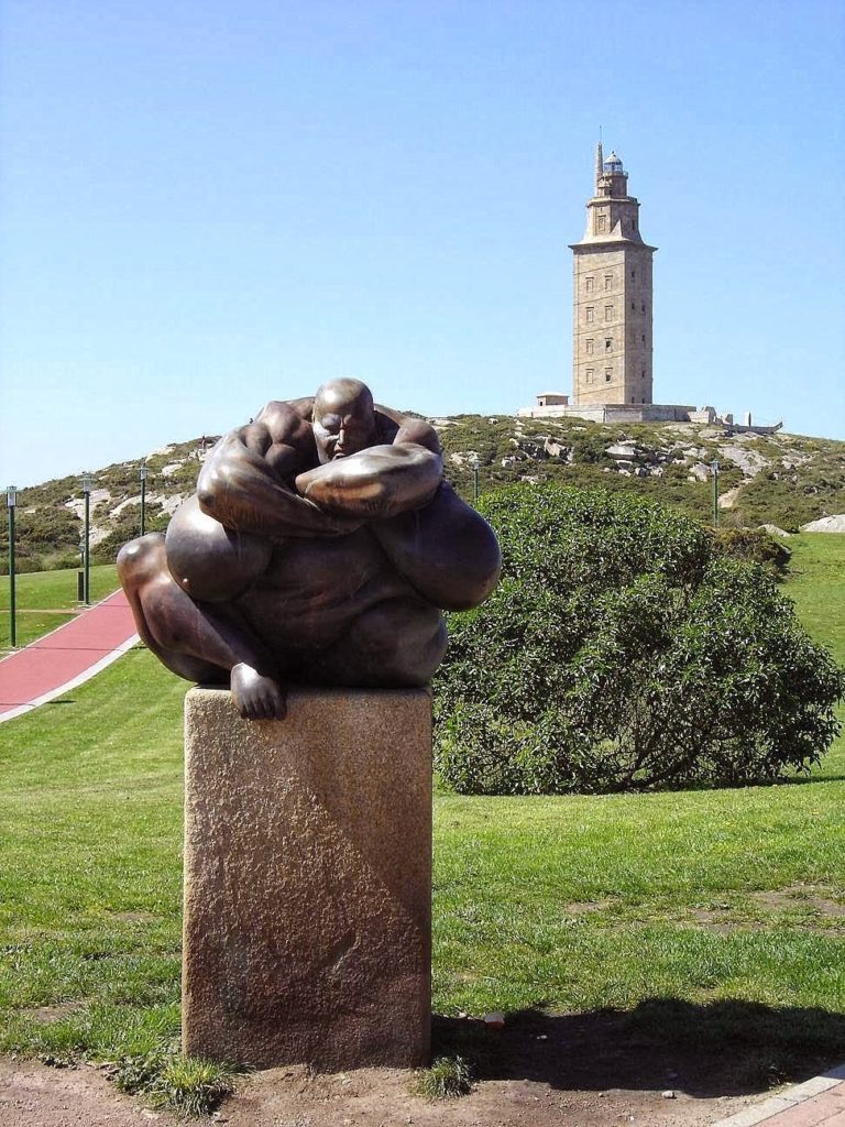 Imagen de la Torre de Hércules al fondo. Captada desde su Parque Escultórico, concretamente con la imagen de Caronte en primer plano