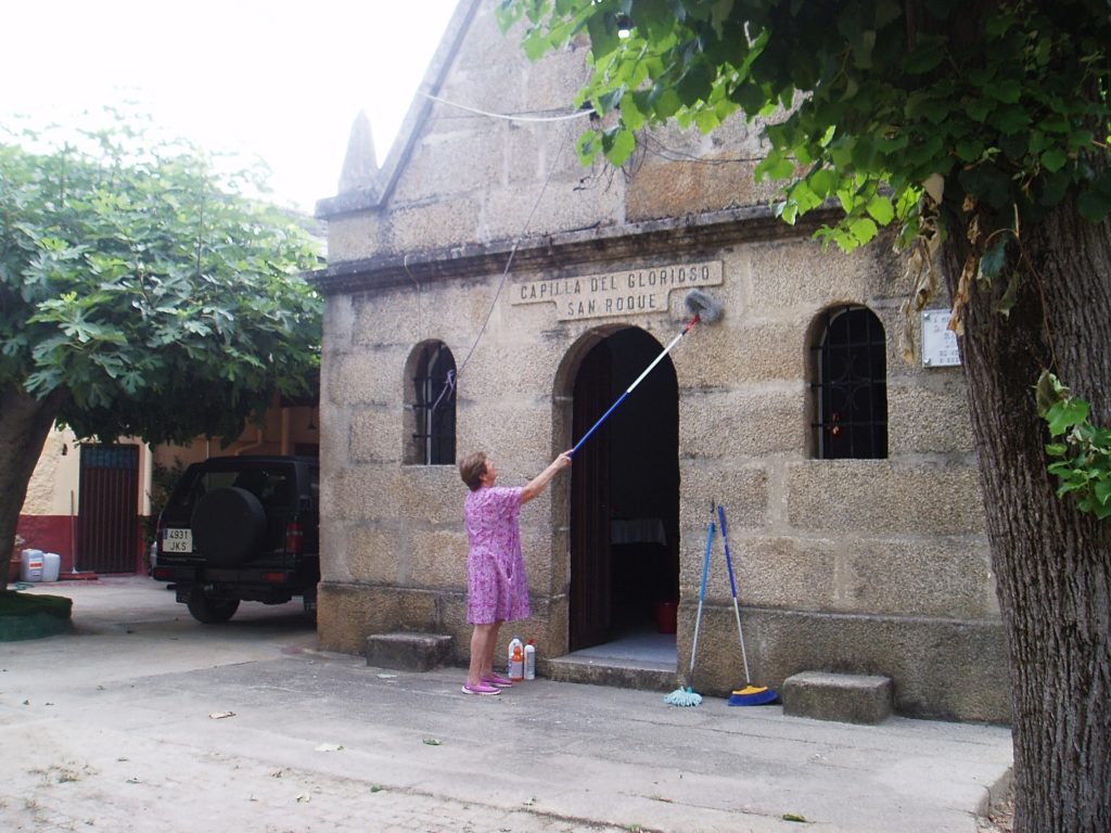 Angélica Carballo Ferrer limpiando la fachada de la capilla de San Roque en A Rúa Vella
